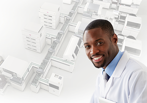 Young man in a medical laboratory coat smiling with the DxA 5000 Automation system in the background
